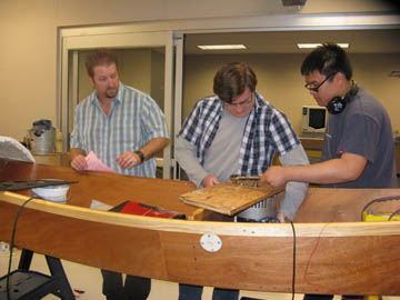 El Toro High School team adviser and teacher Doug Ford, left, observes students James Ryan and Hau Bui as they work on the Solar Cup boat during lunch time. Ryan is the president of the Solar Boat Club.